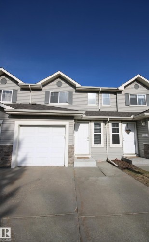 Gray vinyl siding exterior with stone veneer accents - 11 230 Edwards Drive, Edmonton, AB - Outdoor With Facade