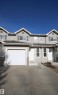 Gray vinyl siding exterior with stone veneer accents - 11 230 Edwards Drive, Edmonton, AB  - Outdoor With Facade 