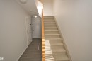 Carpeted staircase with light wood handrail, white painted walls, and wood-finish flooring in the hallway - 11 230 Edwards Drive, Edmonton, AB  - Indoor Photo Showing Other Room 