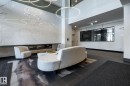 Lobby area featuring a full-height marble-look wall with an integrated linear fireplace, illuminated by contemporary circular pendant lighting - 108 7463 May Common, Edmonton, AB  - Indoor Photo Showing Other Room 