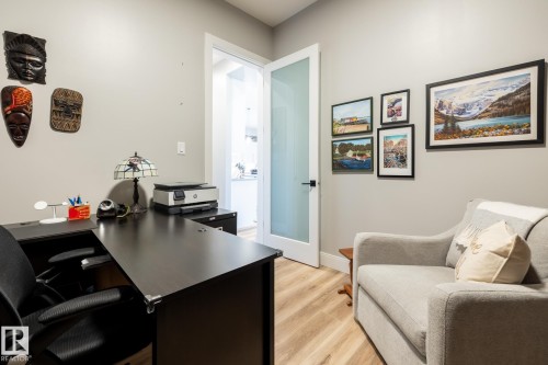 Office space featuring wood-finish flooring, a white opaque glass door, and neutral wall tones - 108 7463 May Common, Edmonton, AB - Indoor Photo Showing Office