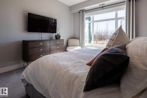 Expansive window framing outdoor scenery - 108 7463 May Common, Edmonton, AB - Indoor Photo Showing Bedroom