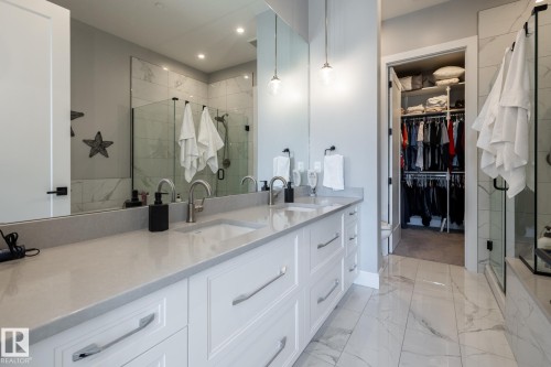 Bathroom featuring a dual vanity with light-toned countertops, undermount sinks, and chrome-finish fixtures - 108 7463 May Common, Edmonton, AB - Indoor Photo Showing Bathroom