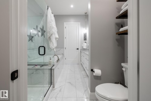 Bathroom featuring a glass-enclosed shower, a built-in bathtub with marble-look tile surround, a double vanity with white cabinetry, light gray walls, and white tile flooring - 108 7463 May Common, Edmonton, AB - Indoor Photo Showing Bathroom