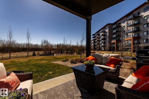 Covered patio with an outdoor area rug, offering direct access to a landscaped green space - 108 7463 May Common, Edmonton, AB - Outdoor