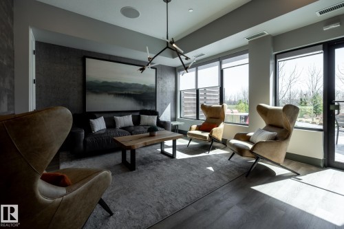Contemporary interior featuring wood-finish flooring, a linear chandelier, and floor-to-ceiling windows with roller shades - 108 7463 May Common, Edmonton, AB - Indoor Photo Showing Living Room