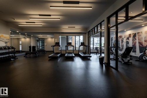 Fitness center featuring a spacious layout with black rubber flooring - 108 7463 May Common, Edmonton, AB - Indoor Photo Showing Gym Room