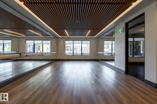 Spacious studio with wood-finish flooring and a slatted wood-panel ceiling - 108 7463 May Common, Edmonton, AB - Indoor Photo Showing Other Room