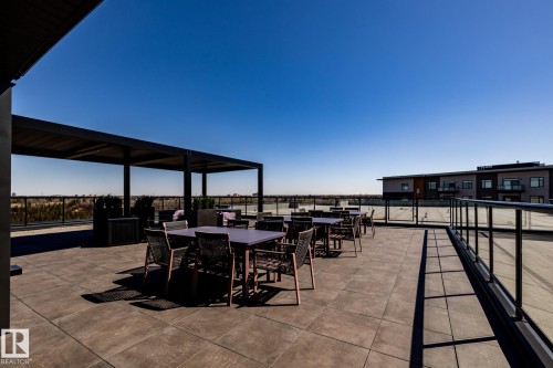 Expansive rooftop terrace featuring large format patio tiles and a contemporary black metal pergola - 108 7463 May Common, Edmonton, AB - Outdoor