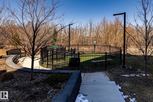 Outdoor fenced pet area featuring artificial turf, a waste station, and perimeter lighting - 108 7463 May Common, Edmonton, AB - Outdoor