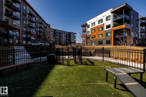 Community green space featuring artificial turf, black metal fencing, and integrated agility equipment - 108 7463 May Common, Edmonton, AB - Outdoor