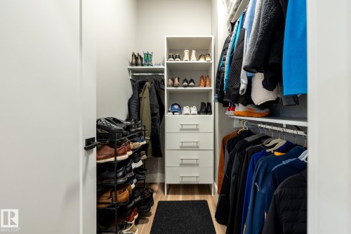 Walk-in closet featuring light wood-finish flooring, white walls, and a white shelving system with integrated drawers - 108 7463 May Common, Edmonton, AB - Indoor With Storage