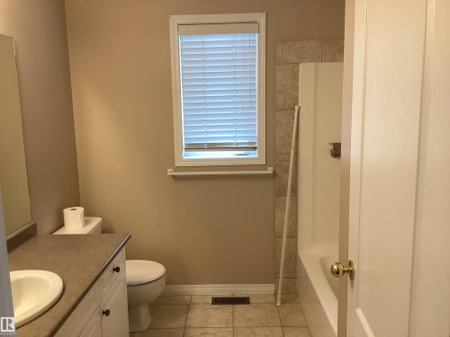 Bathroom featuring a white vanity with a composite countertop, an undermount sink, and paneled cabinetry - 54 Leonard Drive, St. Albert, AB - Indoor Photo Showing Bathroom