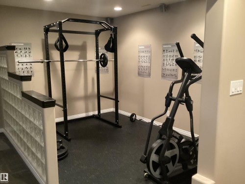 Dedicated fitness area featuring rubber flooring, recessed lighting, and a glass block half-wall - 54 Leonard Drive, St. Albert, AB - Indoor Photo Showing Gym Room