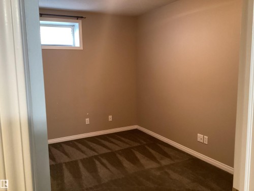 Compact room featuring light brown walls, dark patterned carpeting, and white trim - 54 Leonard Drive, St. Albert, AB - Indoor Photo Showing Other Room