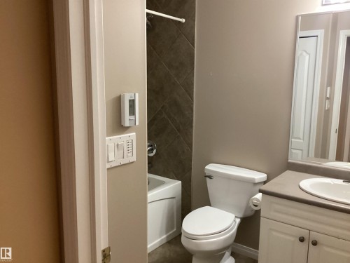 Bathroom featuring a built-in vanity with a white basin and grey countertop, adjacent to a white toilet - 54 Leonard Drive, St. Albert, AB - Indoor Photo Showing Bathroom