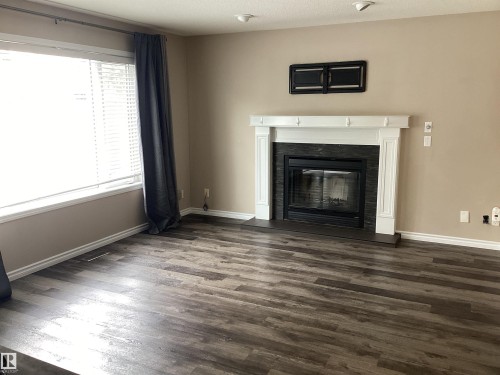 Living space featuring a prominent fireplace with a white mantel and black tile surround, set against neutral wall tones - 54 Leonard Drive, St. Albert, AB - Indoor Photo Showing Living Room With Fireplace