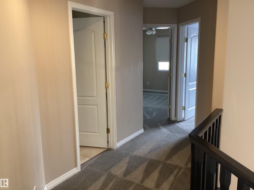 Hallway featuring patterned carpet flooring, white baseboards, and neutral wall paint - 54 Leonard Drive, St. Albert, AB - Indoor Photo Showing Other Room