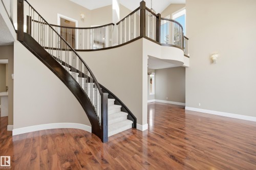Grand curved staircase with dark wood-finish railing and carpeted treads - 394 Walker Road, Edmonton, AB - Indoor Photo Showing Other Room