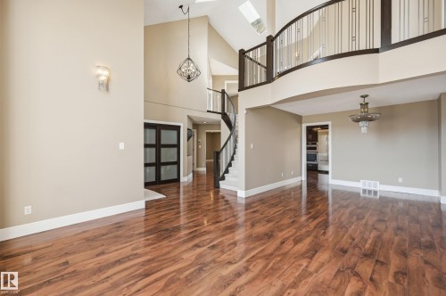 Two-story foyer with high ceilings, wood-finish flooring, and a curved staircase featuring dark wood newel posts and railings - 394 Walker Road, Edmonton, AB - Indoor Photo Showing Other Room