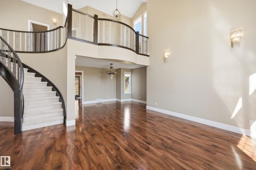 Grand foyer featuring a curved staircase with carpeted treads and dark wood banister - 394 Walker Road, Edmonton, AB - Indoor Photo Showing Other Room