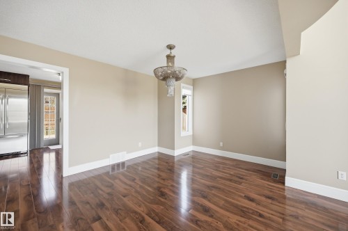 Spacious room featuring wood-finish flooring, a tiered glass chandelier, and neutral wall tones - 394 Walker Road, Edmonton, AB - Indoor Photo Showing Other Room
