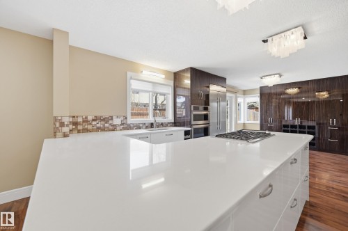 Kitchen featuring a large white island with a built-in gas cooktop, sleek white cabinetry, and stainless steel appliances - 394 Walker Road, Edmonton, AB - Indoor Photo Showing Kitchen With Upgraded Kitchen