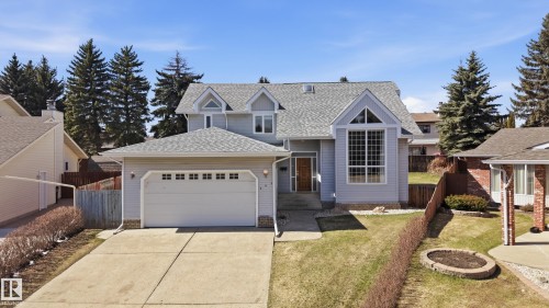 Two-story residence featuring light gray siding, a prominent front window with grid patterns, an attached two-car garage, and a concrete driveway - 394 Walker Road, Edmonton, AB - Outdoor With Facade