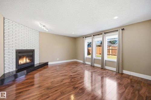 Contemporary fireplace featuring a white brick surround and a black stone hearth - 394 Walker Road, Edmonton, AB - Indoor Photo Showing Other Room With Fireplace