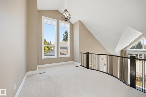Open loft area featuring an accent wall, vaulted ceilings, and a geometric chandelier - 394 Walker Road, Edmonton, AB - Indoor Photo Showing Other Room
