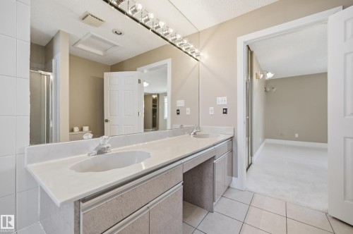Double vanity with integrated sinks, white tile flooring, ample counter space, and a large wall mirror - 394 Walker Road, Edmonton, AB - Indoor Photo Showing Bathroom