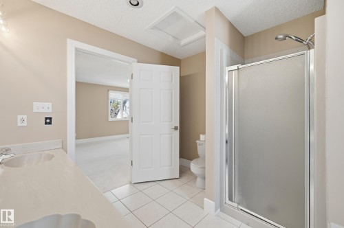 Dual sink vanity with light countertop, white tile flooring, and glass-enclosed shower - 394 Walker Road, Edmonton, AB - Indoor