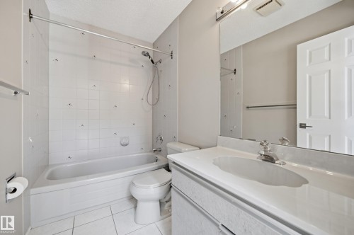 Full bathroom featuring a tub-shower combination with tiled surround, a white toilet, and a vanity with an integrated sink and mirror - 394 Walker Road, Edmonton, AB - Indoor Photo Showing Bathroom