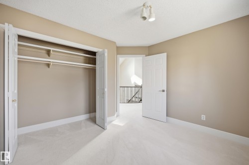 Carpeted room featuring a double bifold closet with shelving and hanging rods - 394 Walker Road, Edmonton, AB - Indoor Photo Showing Other Room