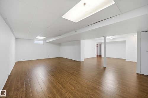 Expansive lower level featuring wood-finish flooring, recessed lighting, drop ceiling, and a bright white paint scheme - 394 Walker Road, Edmonton, AB - Indoor