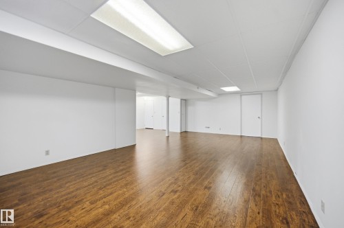 Spacious room featuring wood-finish flooring, white walls, and a drop ceiling with recessed lighting - 394 Walker Road, Edmonton, AB - Indoor Photo Showing Other Room