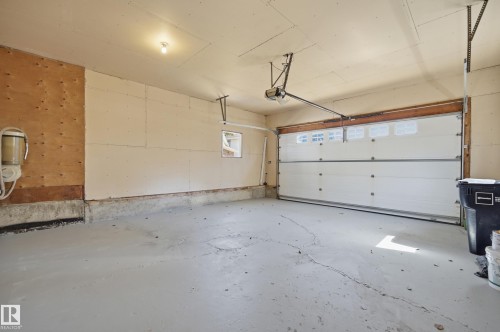 Attached garage featuring a concrete floor, automatic garage door opener, and a white paneled garage door with upper window inserts - 394 Walker Road, Edmonton, AB - Indoor Photo Showing Garage