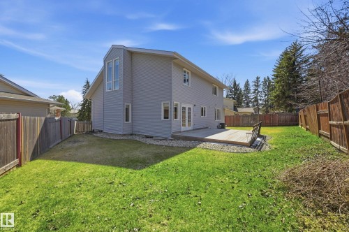 Spacious rear yard with a wooden privacy fence, a large wood deck, and a multi-panel glass door entry - 394 Walker Road, Edmonton, AB - Outdoor With Exterior