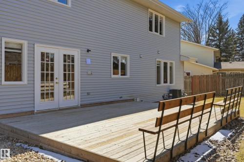 Expansive wood deck with built-in bench seating, featuring direct access via glass-paned French doors - 394 Walker Road, Edmonton, AB - Outdoor With Exterior
