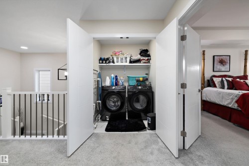Dedicated laundry closet featuring a stacked washer and dryer, integrated shelving, and bi-fold doors - 82 Wingate Way, Fort Saskatchewan, AB - Indoor