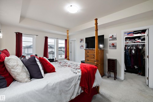 Spacious bedroom featuring light neutral wall tones, plush gray carpet, a ceiling-mounted light fixture, and two large windows providing ample natural illumination - 82 Wingate Way, Fort Saskatchewan, AB - Indoor Photo Showing Bedroom