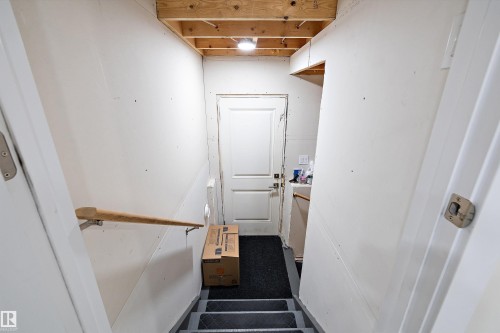 Staircase with wood handrail, white walls, and exposed ceiling joists - 82 Wingate Way, Fort Saskatchewan, AB - Indoor Photo Showing Other Room