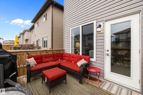 Private outdoor deck with wood railing, featuring grey horizontal siding, a full-light exterior door, and an exterior wall light fixture - 82 Wingate Way, Fort Saskatchewan, AB - Outdoor With Exterior