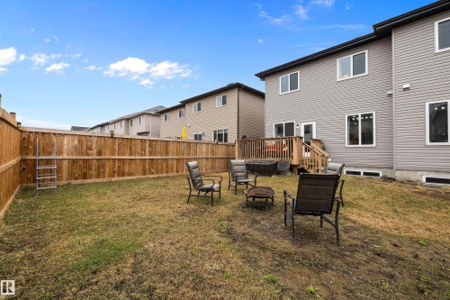 Spacious backyard featuring a full wood privacy fence, a raised wood deck with staircase, and vinyl siding exterior - 82 Wingate Way, Fort Saskatchewan, AB - Outdoor
