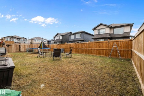 Expansive fenced backyard featuring a wood privacy fence, a grass lawn, and mature perimeter trees - 82 Wingate Way, Fort Saskatchewan, AB - Outdoor With Backyard