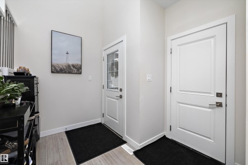 Entryway featuring wood-finish flooring, white baseboards, and two paneled doors with contrasting hardware - 82 Wingate Way, Fort Saskatchewan, AB - Indoor Photo Showing Other Room