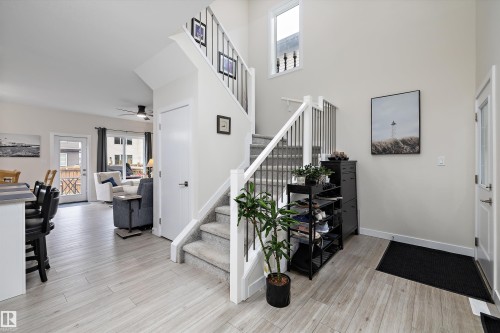 Two-story entryway featuring a carpeted staircase with white risers and black metal balusters - 82 Wingate Way, Fort Saskatchewan, AB - Indoor Photo Showing Other Room