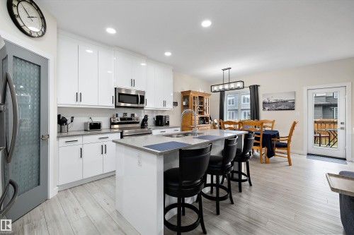 Modern kitchen featuring white cabinetry with dark hardware, stainless steel appliances, and light wood-finish flooring - 82 Wingate Way, Fort Saskatchewan, AB - Indoor Photo Showing Kitchen