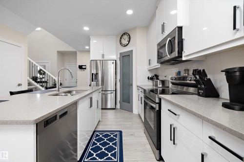 Bright kitchen featuring an island with an undermount sink and a stainless steel dishwasher - 82 Wingate Way, Fort Saskatchewan, AB - Indoor Photo Showing Kitchen With Double Sink With Upgraded Kitchen