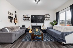 Spacious living area featuring wood-finish flooring, a built-in fireplace with a white mantle, and a ceiling-mounted light fixture - 